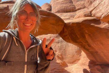Lindsay on a hike posing in front of an arch 